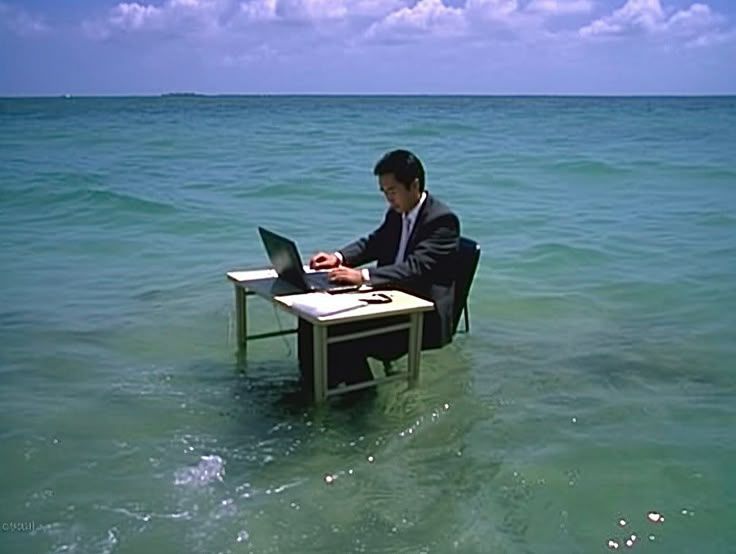 A man working at a desk standing in shallow ocean water